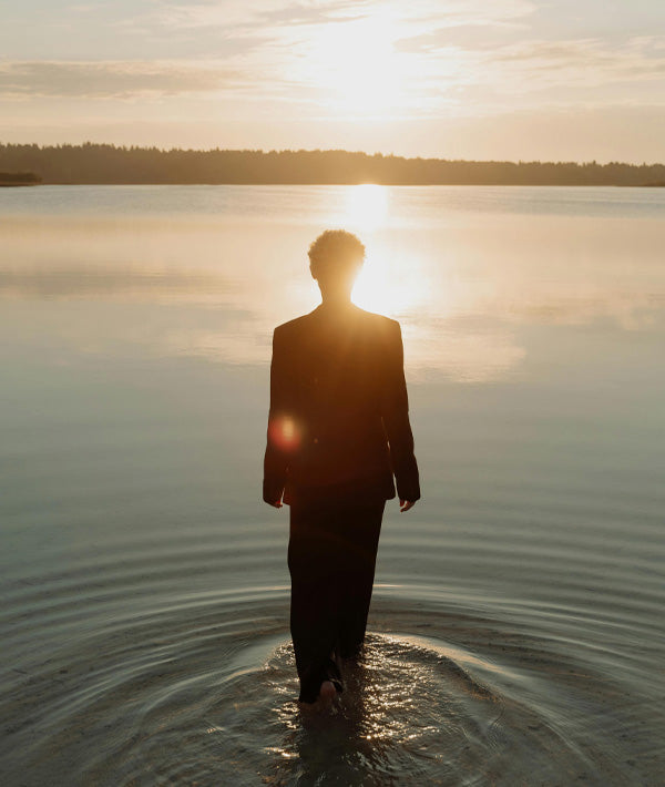 Woman walking into water with beautiful golden sunset. Harnessing the power of the light.